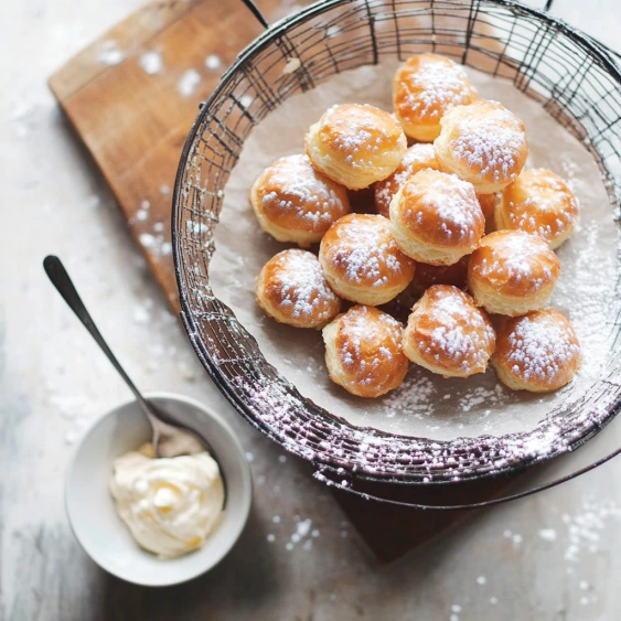 A bowl of powdered sugar covered doughnuts.