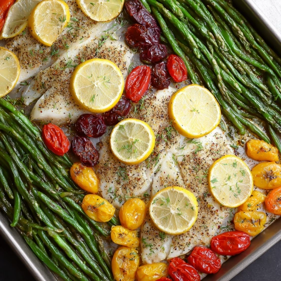 A pan of food with lemon slices and tomatoes.
