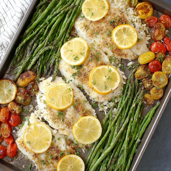 A pan of food with lemon slices and asparagus.