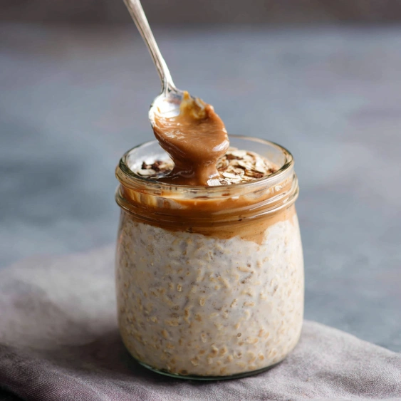 A jar of food with a spoon in it.