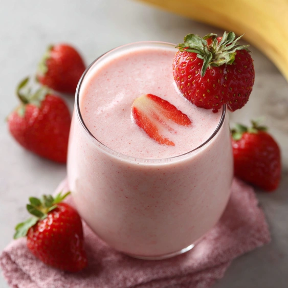 A glass of pink smoothie with strawberries on top.