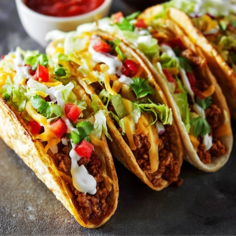 Two tacos with lettuce and cheese.