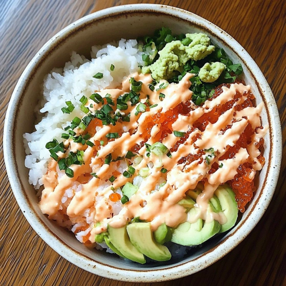 A bowl of sushi with avocado and sauce.