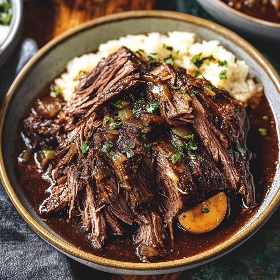 A bowl of beef stew with onions and herbs.
