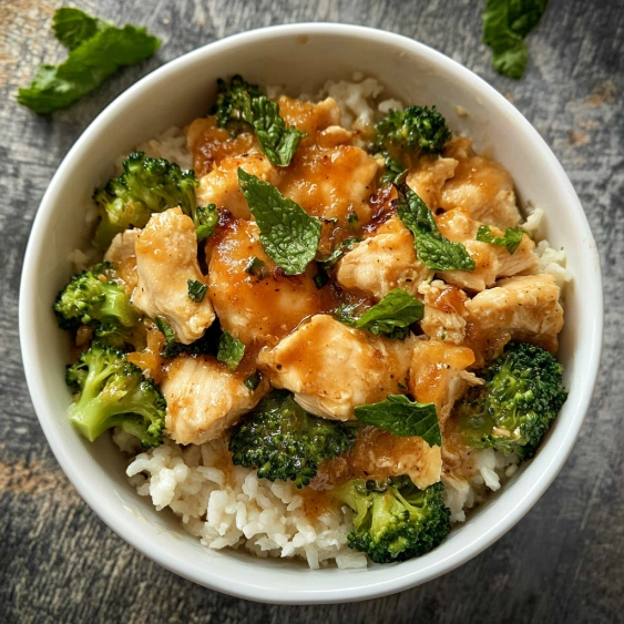 A bowl of rice with chicken and broccoli.