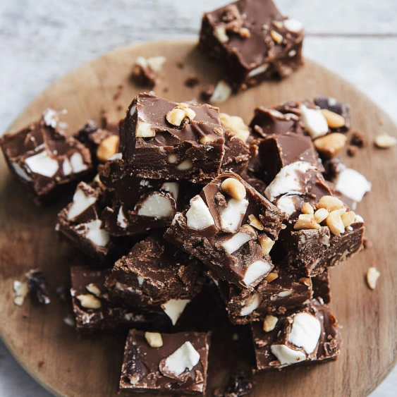 A wooden cutting board with a plate of chocolate and peanut butter squares.
