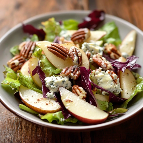 A plate of salad with apples and walnuts.