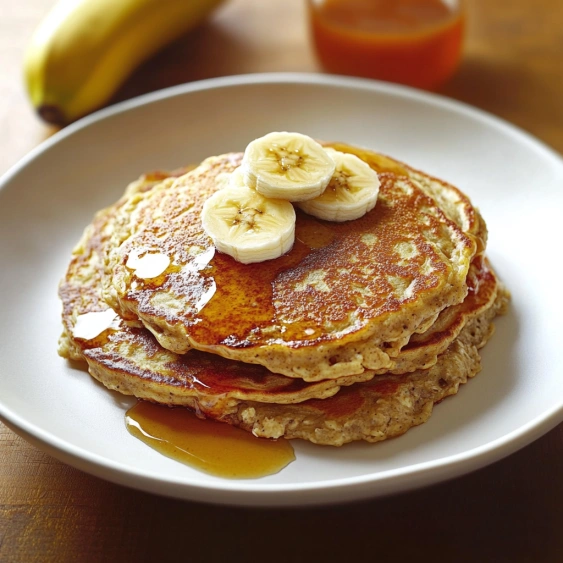 A plate of pancakes with bananas on top.