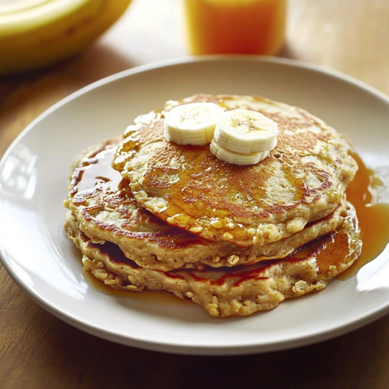A plate of pancakes with bananas on top.