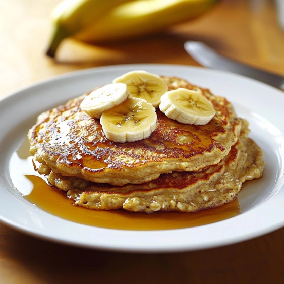 A plate of pancakes with bananas on top.
