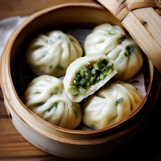 A basket of dumplings with green vegetables inside.