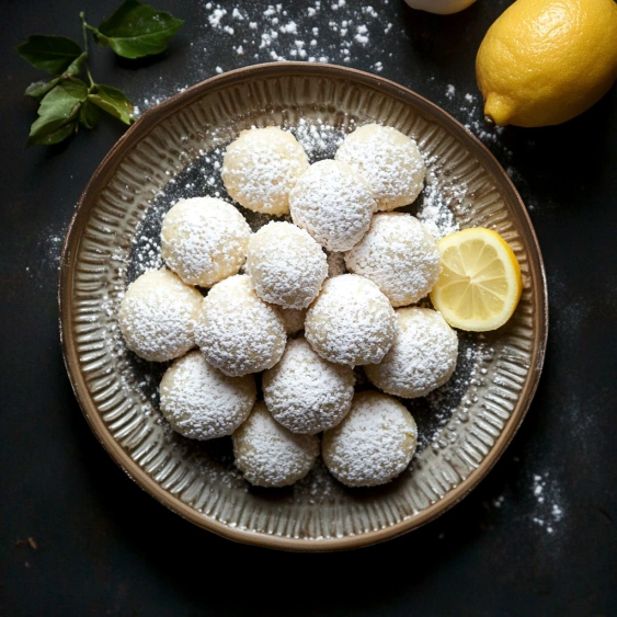 A plate of white powdered sugar covered cookies.