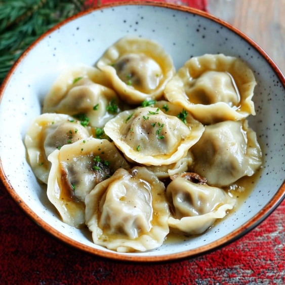 A bowl of pasta with green herbs on top.
