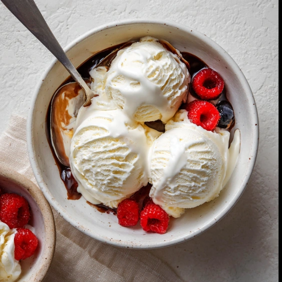 A bowl of ice cream with berries on top.