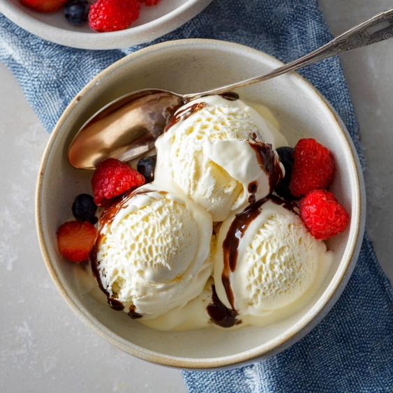 A bowl of ice cream with chocolate sauce and strawberries.