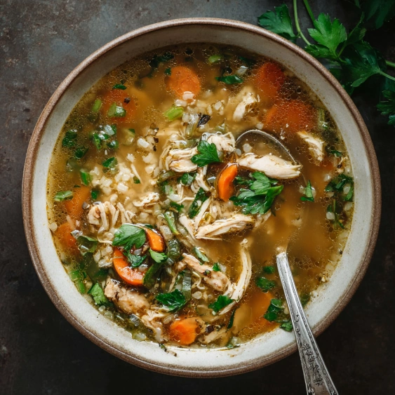 A bowl of soup with chicken and vegetables.