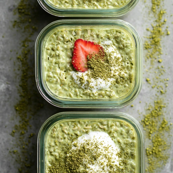 Three glasses of food with strawberries and green stuff.